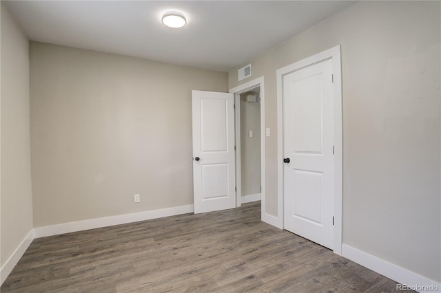 spare room with wood finished floors, visible vents, and baseboards