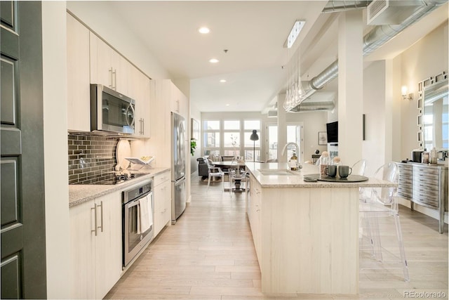 3198 Blake St Unit 502, Denver, CO 80205 - kitchen with stainless steel appliances, a kitchen island with sink, recessed lighting, light wood finished floors, and plenty of natural light
