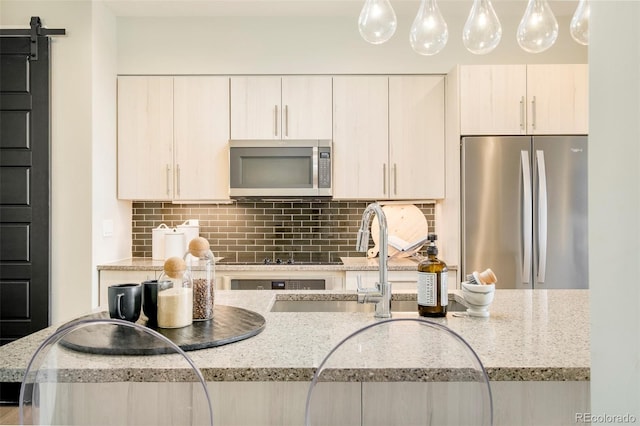 3198 Blake St Unit 502, Denver, CO 80205 - kitchen featuring appliances with stainless steel finishes, decorative backsplash, decorative light fixtures, and light stone countertops