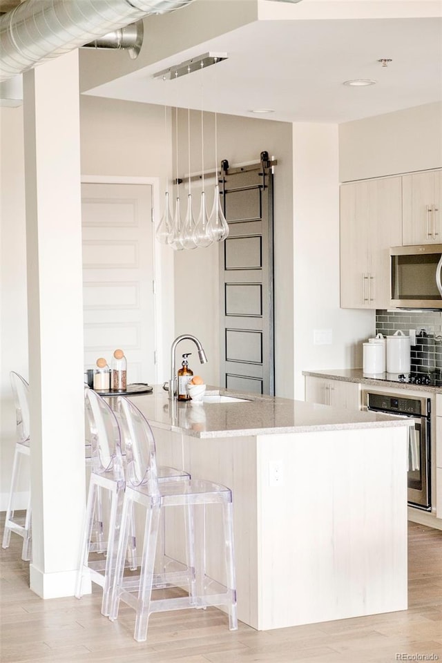 3198 Blake St Unit 502, Denver, CO 80205 - kitchen featuring stainless steel appliances, light stone counters, a kitchen bar, tasteful backsplash, and light wood-style flooring