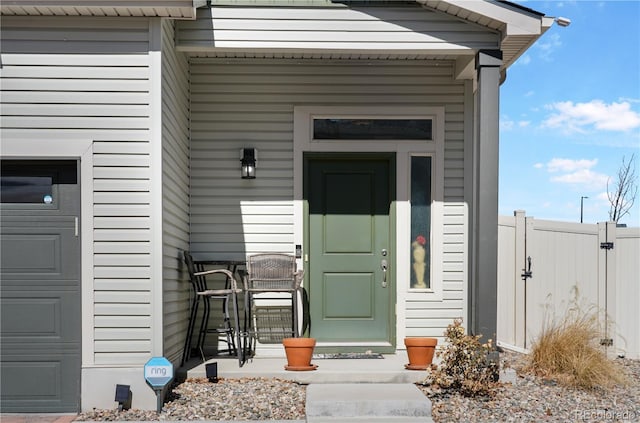 doorway to property featuring a porch, an attached garage, and fence