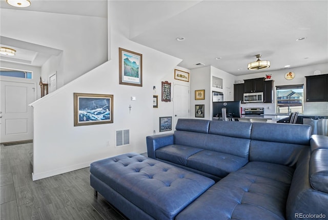 living room with dark wood-style floors, baseboards, visible vents, and recessed lighting