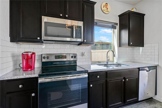 kitchen featuring dark cabinets, stainless steel appliances, and a sink