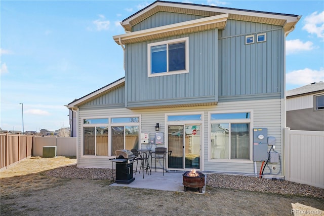 back of house featuring a fire pit, a patio, board and batten siding, and a fenced backyard