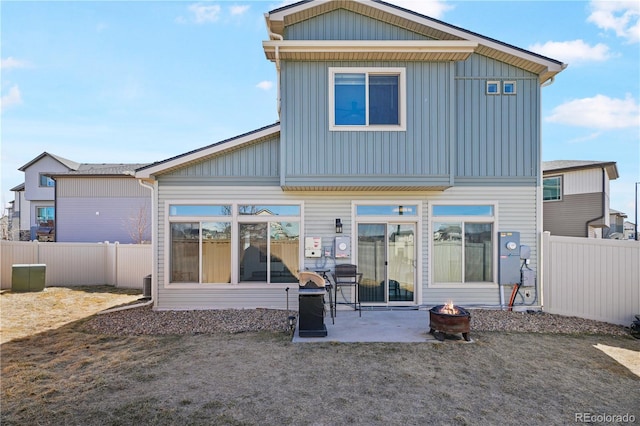 rear view of house with an outdoor fire pit, fence, board and batten siding, and a patio