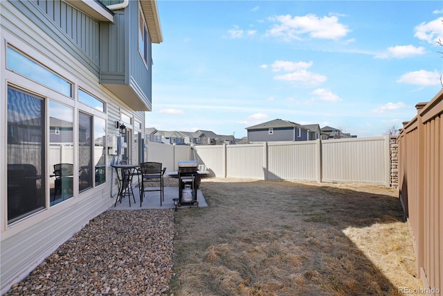 view of yard featuring a patio area, a fenced backyard, and a residential view