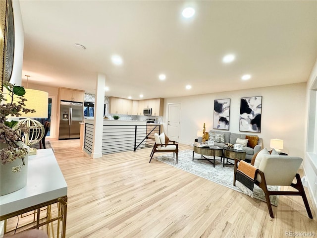 living room featuring baseboards, light wood-style flooring, and recessed lighting