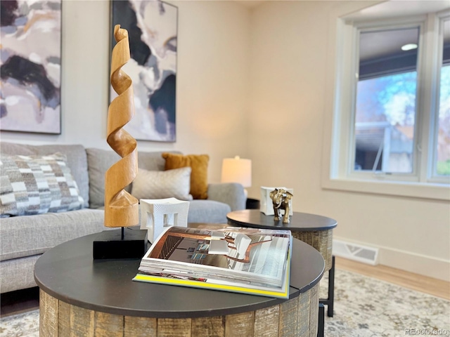 living room with baseboards, visible vents, and wood finished floors