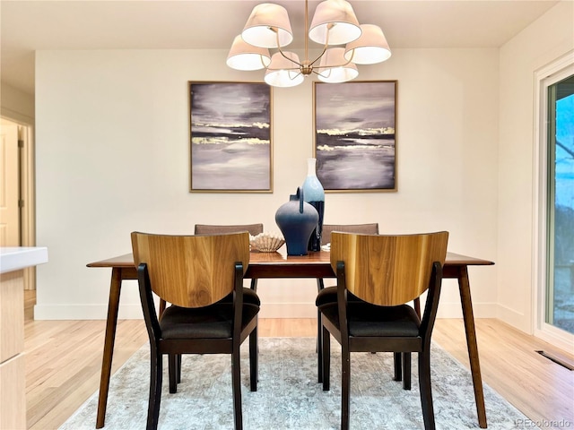 dining area with a chandelier, visible vents, baseboards, and wood finished floors