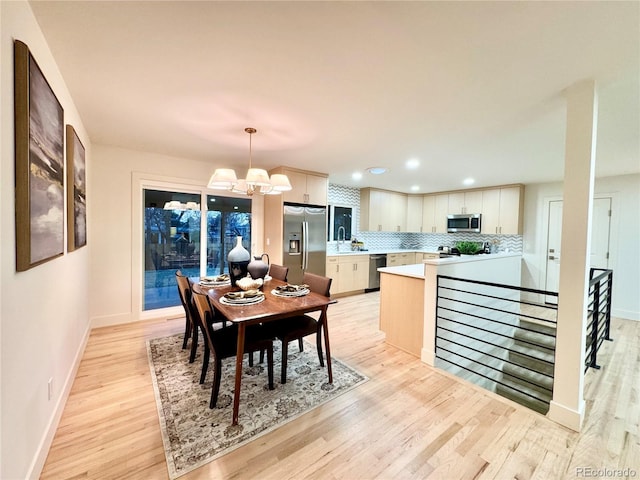 dining space featuring light wood-style floors, recessed lighting, baseboards, and an inviting chandelier