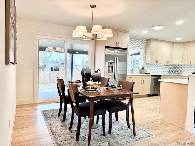 dining space with recessed lighting, baseboards, light wood finished floors, and an inviting chandelier