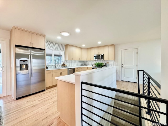 kitchen with light wood finished floors, decorative backsplash, stainless steel appliances, light countertops, and light brown cabinets