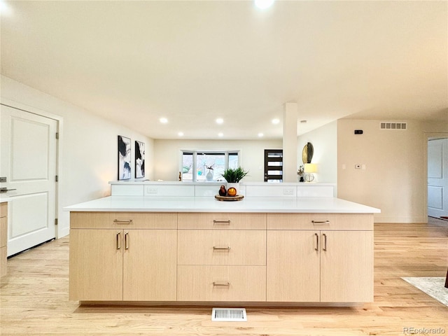 kitchen with light countertops, visible vents, light wood finished floors, and light brown cabinets