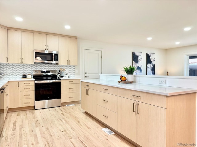 kitchen featuring appliances with stainless steel finishes, light countertops, backsplash, and light brown cabinetry