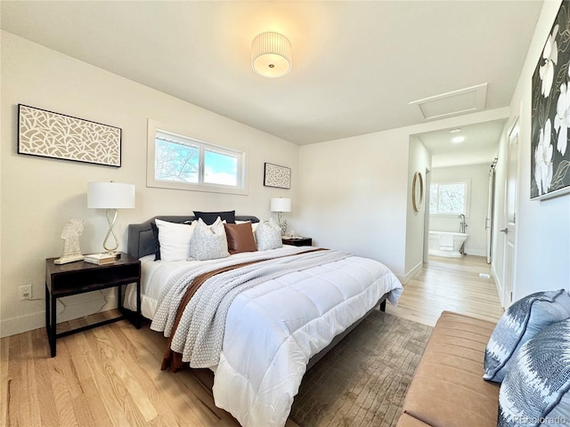 bedroom with attic access, light wood-style floors, and baseboards