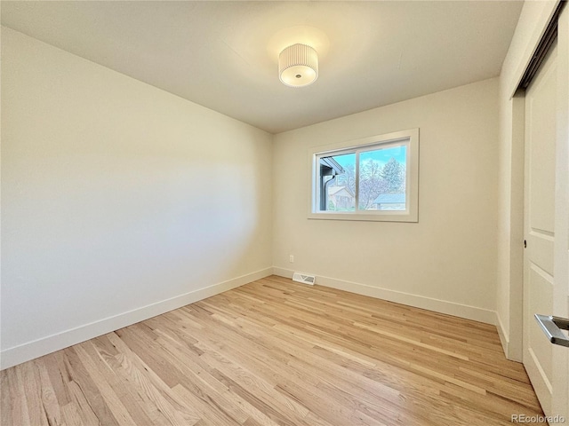 unfurnished room featuring light wood-style flooring, visible vents, and baseboards