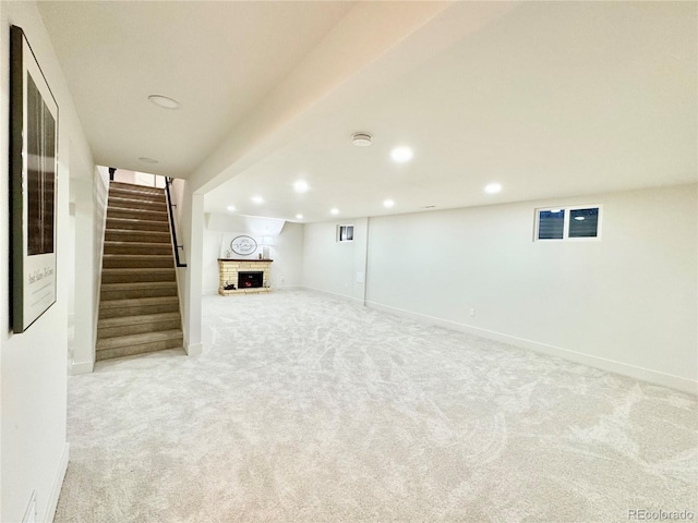 finished basement with light carpet, a brick fireplace, stairway, and recessed lighting