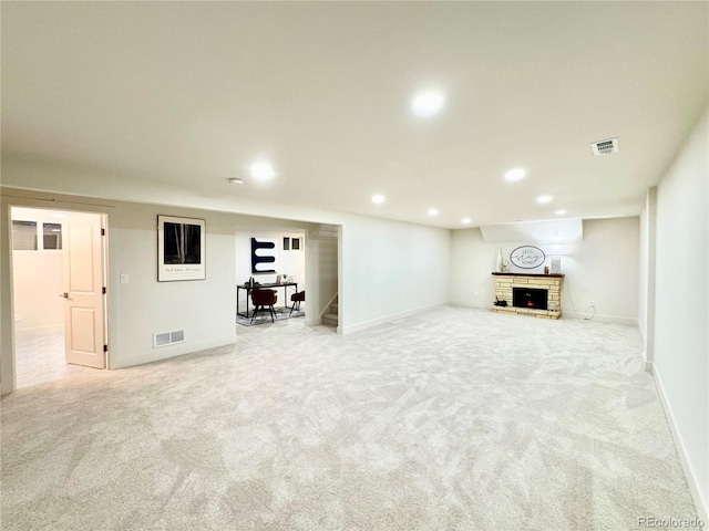 finished basement with a brick fireplace, visible vents, and carpet flooring