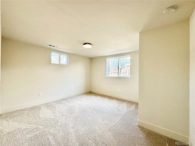 carpeted empty room with visible vents, a wealth of natural light, and baseboards