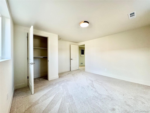 unfurnished bedroom featuring a walk in closet, a closet, light colored carpet, visible vents, and baseboards