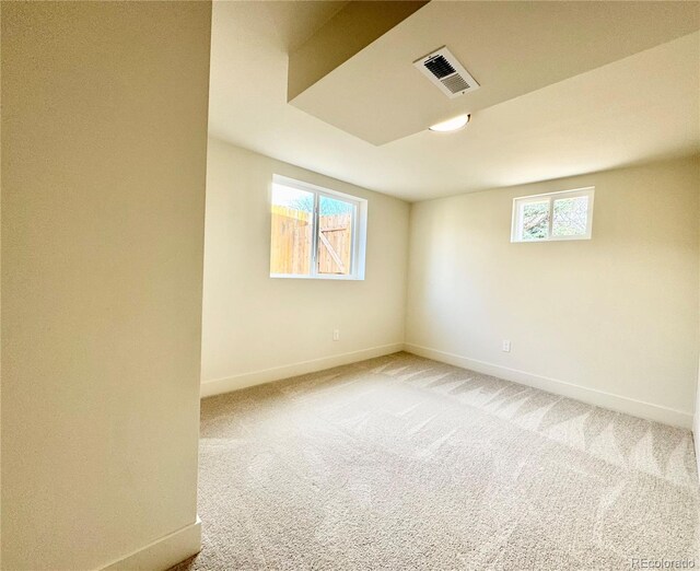 spare room with plenty of natural light, visible vents, baseboards, and light colored carpet