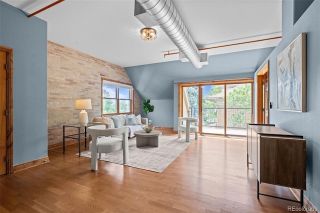3299 Lowell Blvd Unit 204, Denver, CO 80211 - living room featuring brick wall, wood finished floors, vaulted ceiling, and baseboards