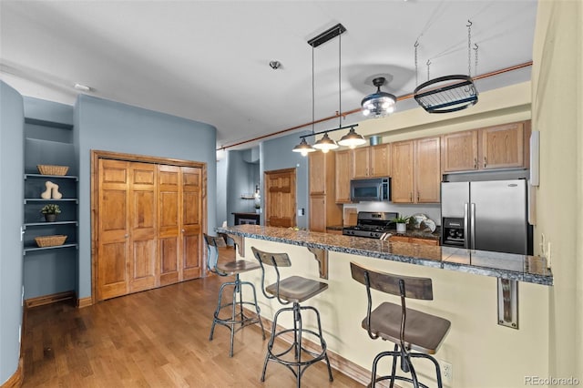 3299 Lowell Blvd Unit 204, Denver, CO 80211 - kitchen with stainless steel appliances, a breakfast bar area, hanging light fixtures, wood finished floors, and brown cabinets