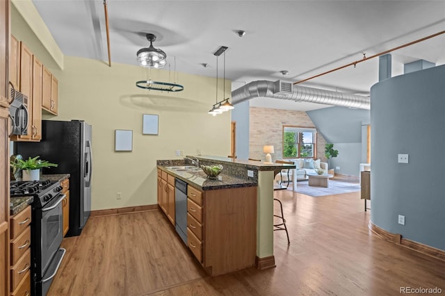 3299 Lowell Blvd Unit 204, Denver, CO 80211 - kitchen featuring a breakfast bar, appliances with stainless steel finishes, a peninsula, open floor plan, and light wood-style floors