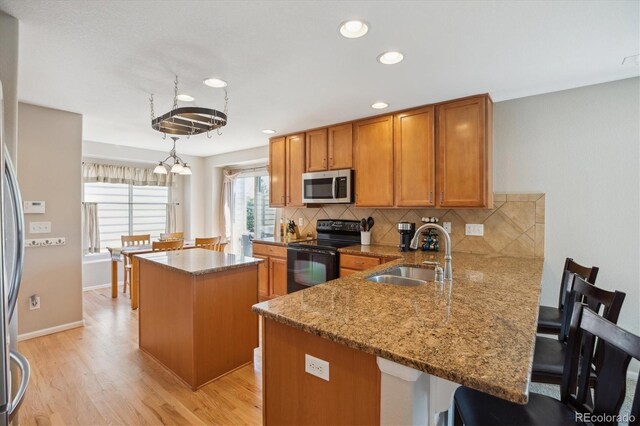 11866 High Desert Rd, Parker, CO 80134 - kitchen with stainless steel microwave, black electric range oven, a sink, brown cabinetry, and a kitchen island