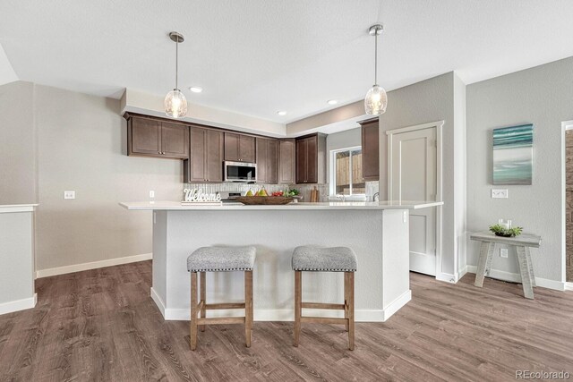 kitchen featuring a center island, dark brown cabinetry, hardwood / wood-style flooring, and hanging light fixtures