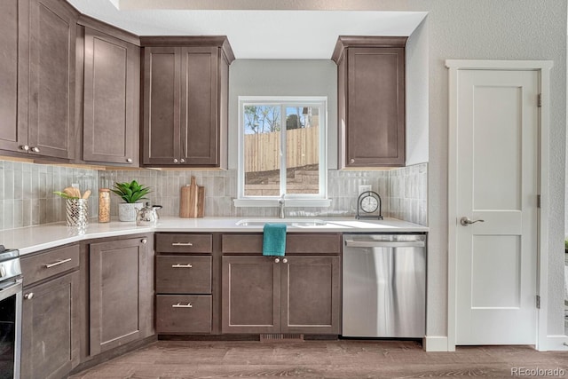 kitchen featuring decorative backsplash, dark brown cabinets, sink, dishwasher, and hardwood / wood-style floors