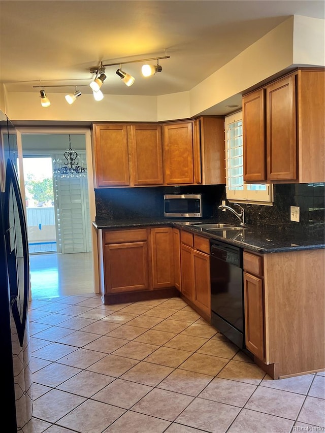 kitchen featuring decorative backsplash, dark stone countertops, light tile patterned flooring, black appliances, and sink