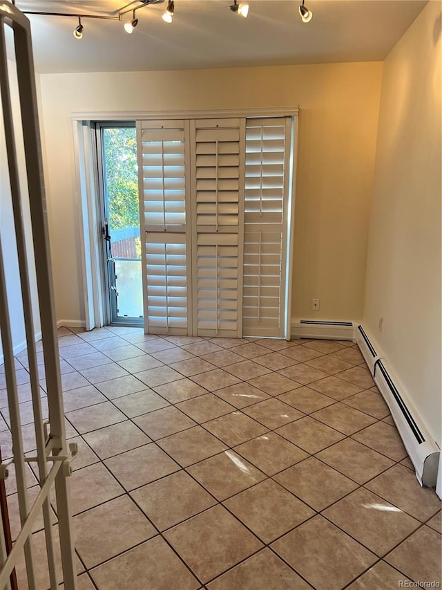 unfurnished room featuring rail lighting, a baseboard heating unit, and light tile patterned floors