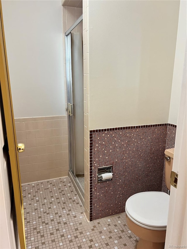 bathroom featuring tile walls, tile patterned floors, toilet, and an enclosed shower