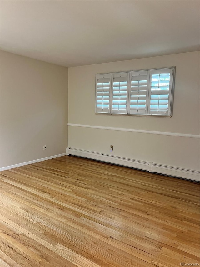 spare room featuring a baseboard radiator and light wood-type flooring