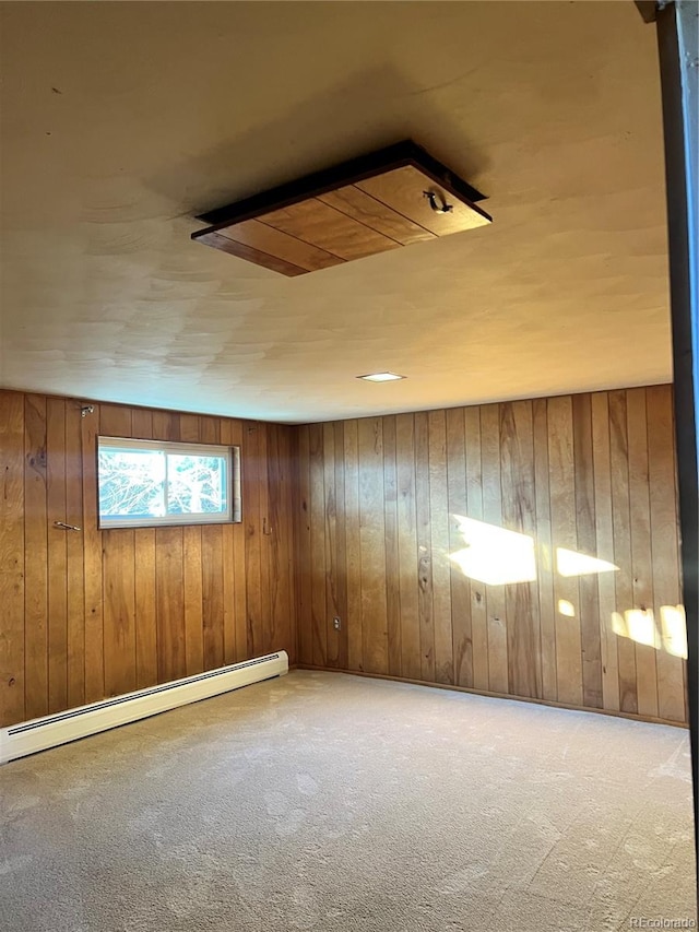 empty room featuring carpet floors, wooden walls, and a baseboard radiator