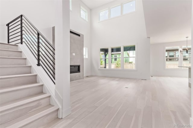 5608 Grandville Ave, Longmont, CO 80503 - unfurnished living room featuring a fireplace, a high ceiling, stairs, and healthy amount of natural light
