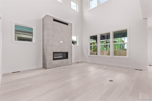 5608 Grandville Ave, Longmont, CO 80503 - unfurnished living room with a fireplace, a towering ceiling, and wood finished floors