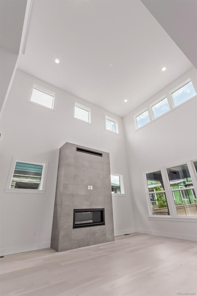 5608 Grandville Ave, Longmont, CO 80503 - unfurnished living room with wood finished floors, a tile fireplace, a high ceiling, and recessed lighting