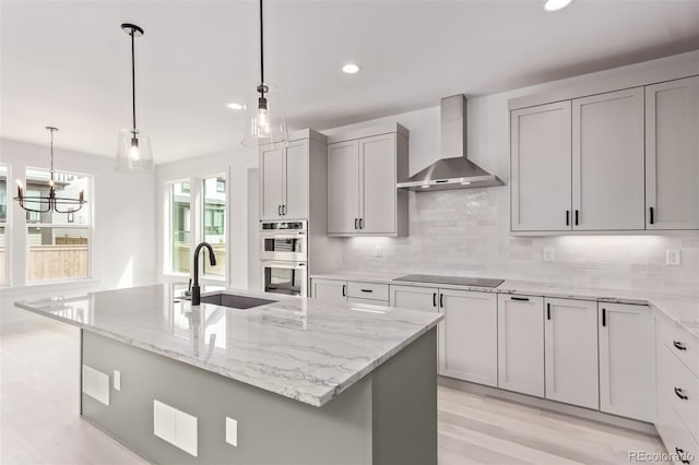 5608 Grandville Ave, Longmont, CO 80503 - kitchen featuring wall chimney exhaust hood, double oven, black electric stovetop, light stone countertops, and light wood-type flooring