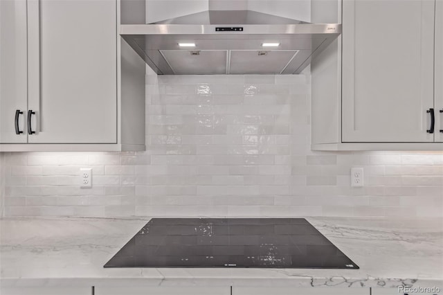 5608 Grandville Ave, Longmont, CO 80503 - kitchen view of extractor fan, black electric cooktop, light stone countertops, and decorative backsplash