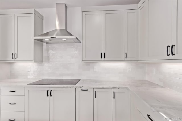 5608 Grandville Ave, Longmont, CO 80503 - kitchen featuring wall chimney range hood, black electric cooktop, backsplash, light stone counters, and white cabinetry