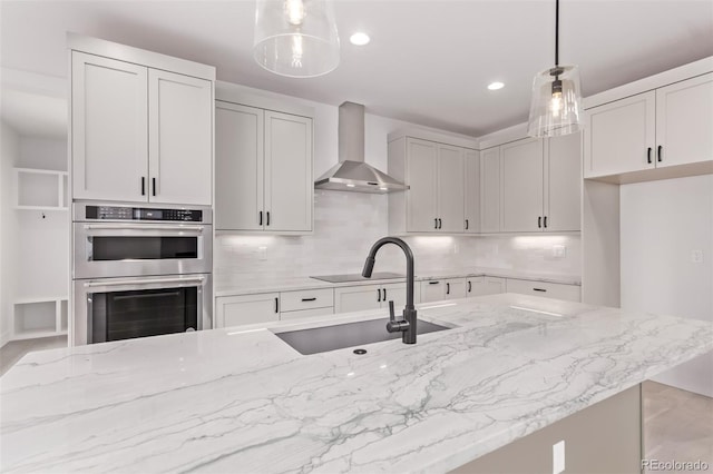 5608 Grandville Ave, Longmont, CO 80503 - kitchen featuring wall chimney exhaust hood, stainless steel double oven, light stone countertops, backsplash, and recessed lighting
