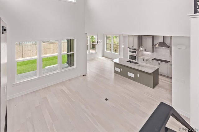 5608 Grandville Ave, Longmont, CO 80503 - kitchen featuring a high ceiling, black electric cooktop, wall chimney range hood, healthy amount of natural light, and double oven