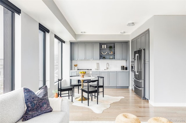 kitchen with gray cabinets, light hardwood / wood-style floors, stainless steel refrigerator, and tasteful backsplash