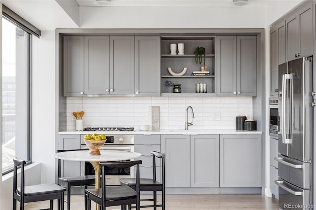 kitchen with gray cabinets, sink, stainless steel refrigerator, and light hardwood / wood-style floors