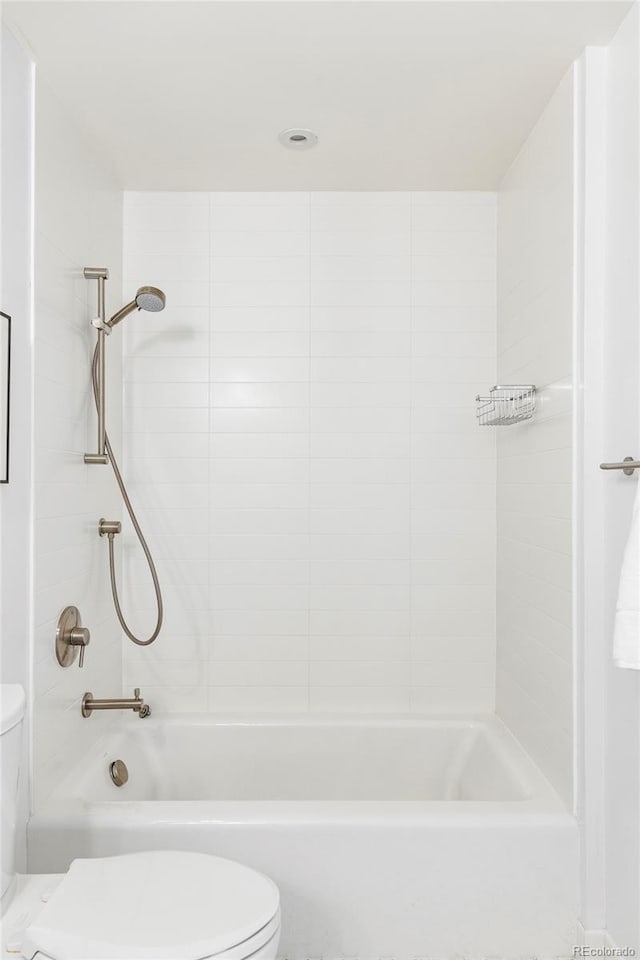 bathroom with tiled shower / bath combo and toilet