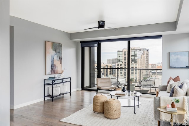 living room featuring ceiling fan, hardwood / wood-style floors, and a wall of windows