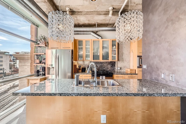 kitchen with a sink, stainless steel refrigerator with ice dispenser, decorative backsplash, and an inviting chandelier