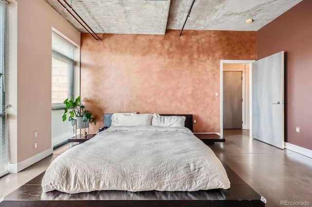 bedroom featuring concrete flooring and baseboards